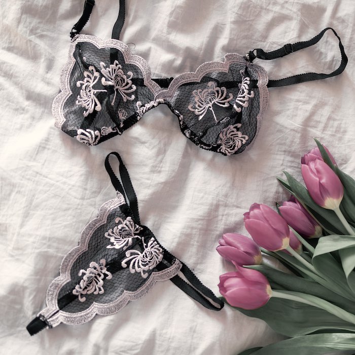 Lingerie and a bouquet  of flowers laying on bed.